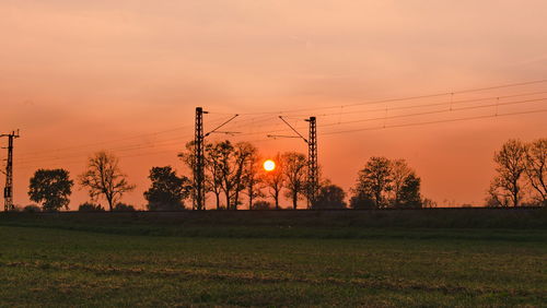 Scenic view of field and railroad against sky during sunset