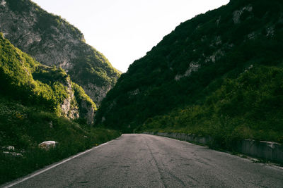 Road amidst trees and mountains against sky