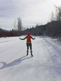 Full length of woman walking on snow covered field against sky