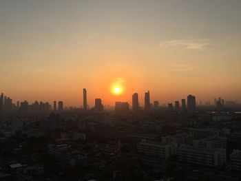 Modern buildings in city against sky during sunset