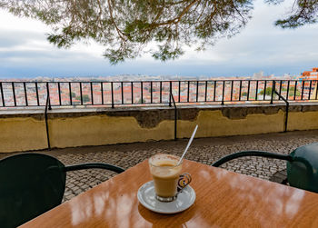 Coffee on table by sea against sky