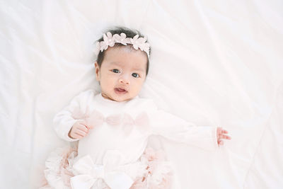 High angle portrait of baby girl lying on bed