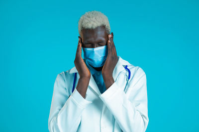 Portrait of man standing against blue background