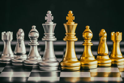 Close-up of chess pieces on board against black background