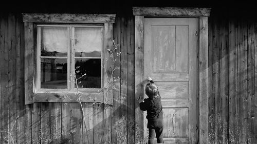 Rear view of boy opening old house door