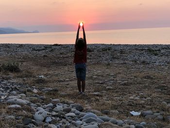 Woman standing on beach against sky during sunset