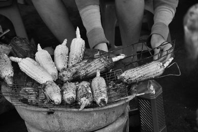 Midsection of man preparing corn on barbecue grill