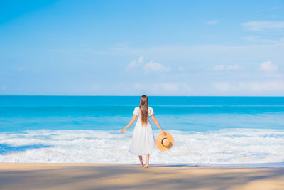 Woman standing at beach against sky