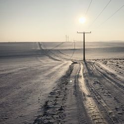 Road amidst land against sky during sunset