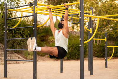 Athletic male exercising chin-ups in playground