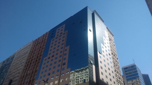 Low angle view of modern buildings against clear blue sky