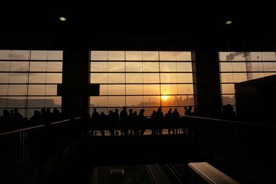 Silhouette people in city against sky during sunset