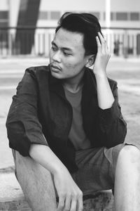 Young man looking away while sitting on street