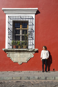 Full length portrait of man standing against red wall