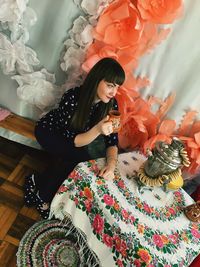 High angle view of young woman having drink while sitting at table