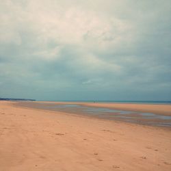 Scenic view of beach against cloudy sky