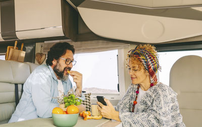 Portrait of smiling friends using mobile phone at home