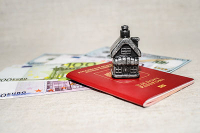 Close-up of money with passport and model home on table