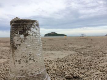 Close-up of water drops on sand against sky