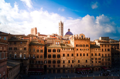 Buildings in city against cloudy sky