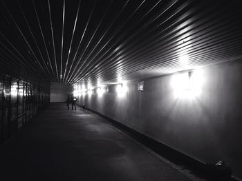 Rear view of woman walking in illuminated tunnel