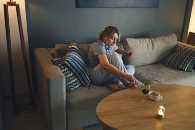 Woman using digital tablet while sitting on sofa at home