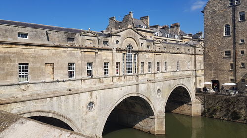 Low angle view of arch bridge over canal against buildings