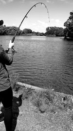 Man fishing in river against sky