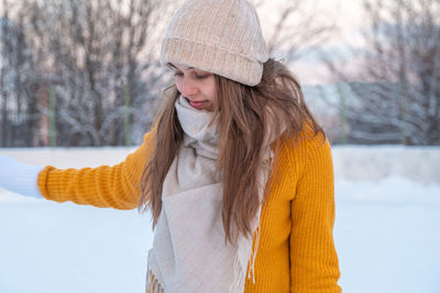 Portrait of happy young woman in yellow jacket skating at the rink