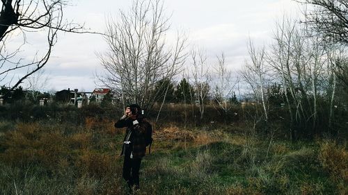 Man photographing on field against sky