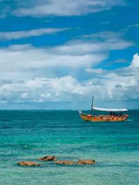 Boat on sea against cloudy sky