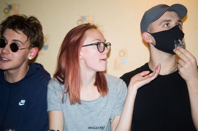 Portrait of young friends looking away against wall