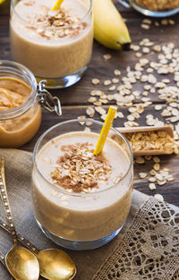 Fresh homemade smoothie with banana, oat flakes and peanut butter on rustic wooden background.
