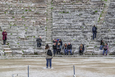 People on staircase against brick wall