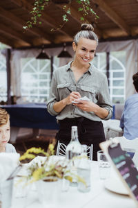 Smiling female owner taking order from customer while standing in restaurant