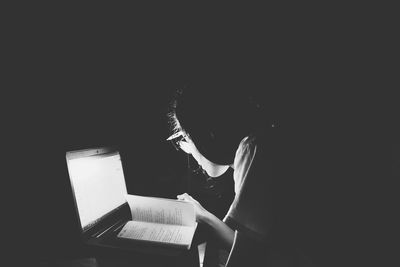 Woman reading book against black background