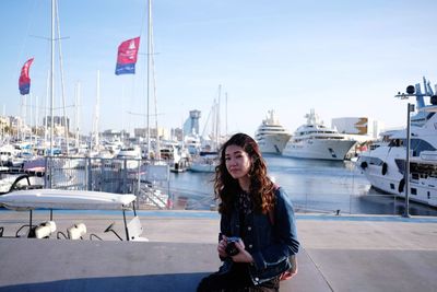 Portrait of young woman in harbor against sky