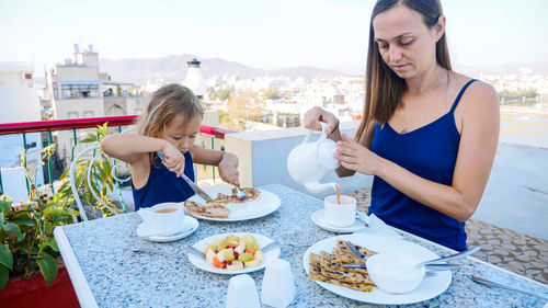 Mother and daughter having breakfast in balcony