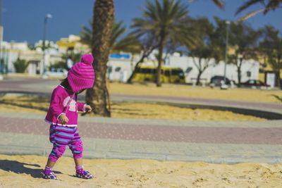 Rear view of woman with pink umbrella against trees in city