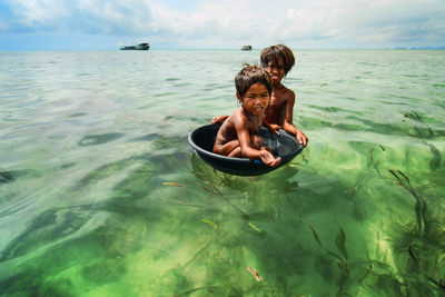 Portrait of shirtless boy in sea against sky