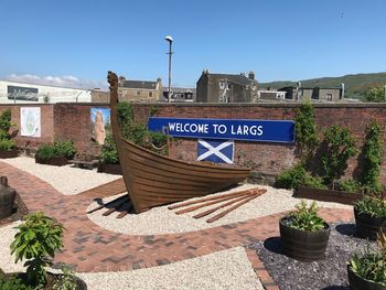 Information sign by building against blue sky