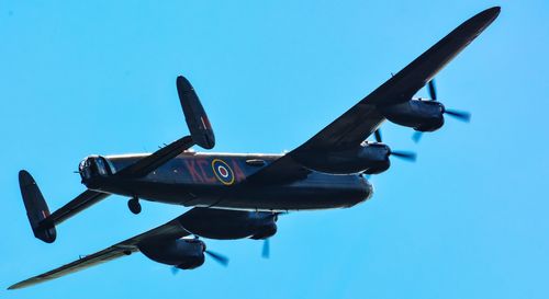 Low angle view of airplane flying against clear blue sky