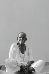 Portrait of man sitting against wall