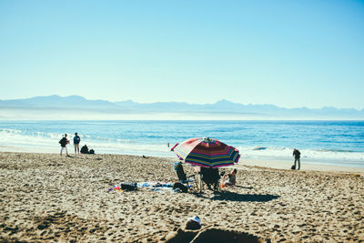 People at beach against clear sky