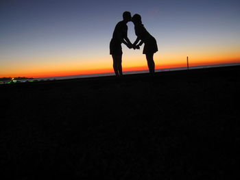 Silhouette of woman standing on beach at sunset