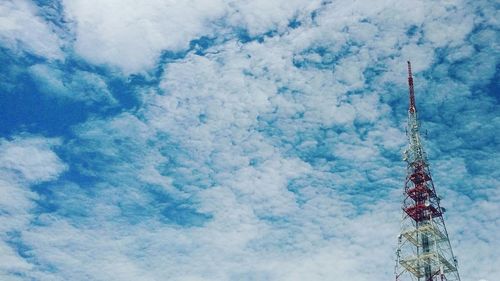 Low angle view of communications tower against cloudy sky