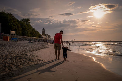 People on beach against sky during sunset