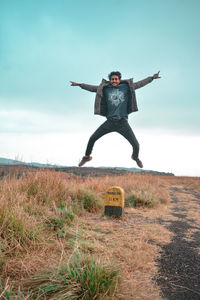Full length of man jumping on field against sky
