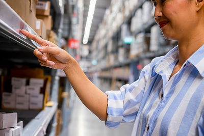 Woman pointing at shelf while standing in warehouse