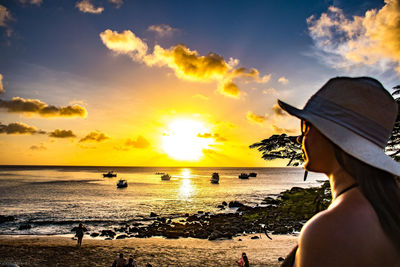 Woman looking at sea against sky during sunset